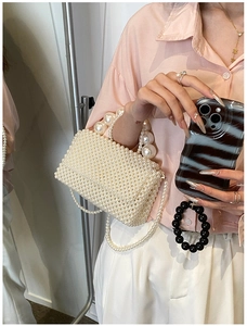 Detail of handcrafted cream pearl woven mini handbag with elegant pearl handle and strap