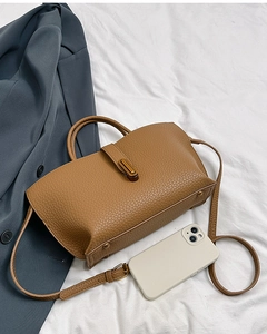Detail of brown litchi pattern leather handbag with gold lock and adjustable strap