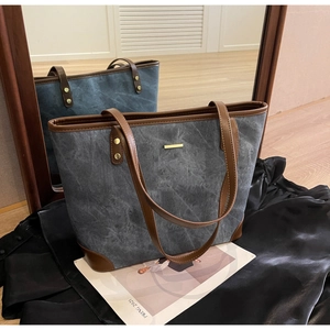 Detail of grey washed canvas tote bag with brown leather accents and metallic trim