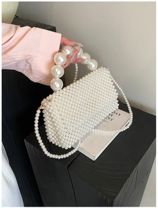 Detail of handcrafted cream pearl woven handbag with large round pearl top handle
