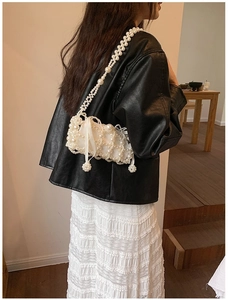 Lifestyle shot of white pearl crossbody bag with silk bow detail and long pearl chain