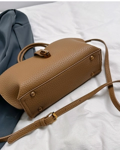 Detail of brown litchi pattern leather tote bag bottom with gold metal protective studs