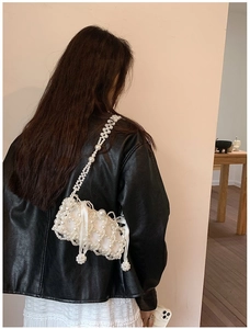 Detailed view of handmade white pearl woven crossbody bag with silk lining on a model