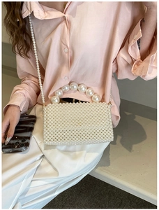 Detail of white pearl woven handbag with large bead handle and long shoulder chain strap