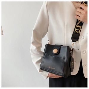 Détail du sac seau noir avec bandoulière à motifs et fermeture à bouton en bois