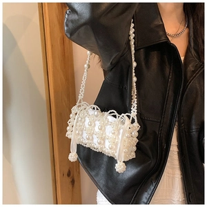 Detail of white handmade pearl woven bag with satin drawstring liner and pearl charm