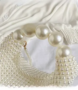 Macro view of woven pearl handbag featuring large pearl handle and elegant bead texture