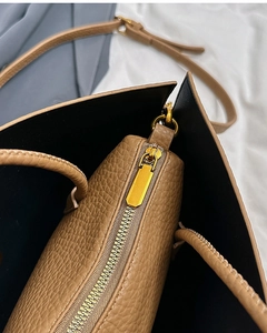 Detail shot of brown lychee grain leather handbag featuring gold hardware and inner zipper