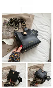 Détails du sac seau noir avec logo doré et bandoulière large en jacquard élégant