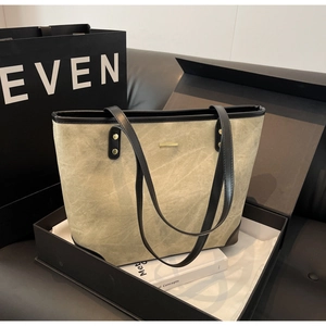 Detail of khaki green tote bag with black trim and gold rivets in premium gift box