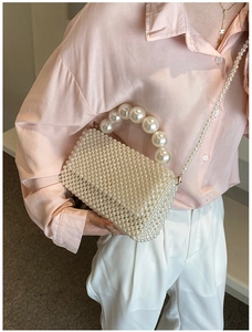 Detail showing elegant white handmade pearl beaded crossbody bag and large pearl handle