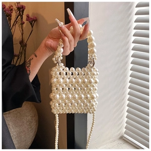 Detailed close-up of handmade white faux pearl woven handbag with silver metal rings