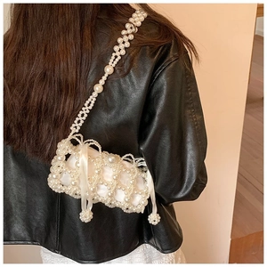 Detail of handmade pearl woven mini bag with satin lining worn over a black leather jacket