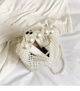 Detail view of large pearl handle and spacious interior of woven pearl evening bag