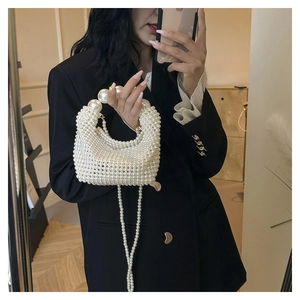 Detail shot of handcrafted white pearl woven handbag with a large beaded round handle