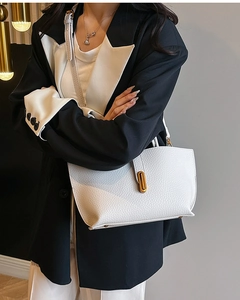 Macro shot showing white lychee grain leather texture and gold oval twist lock on a bucket bag