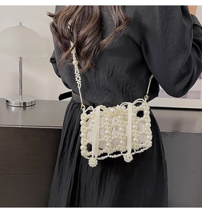Detail of white handmade pearl bucket bag with woven hollow design and satin inner pouch