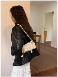 Detail of handcrafted white pearl crossbody bag with ribbon bow on a fashion model
