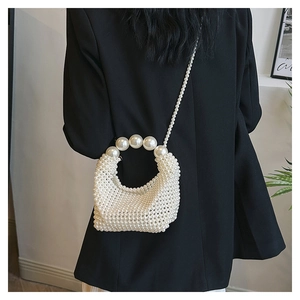 Detail of handcrafted white pearl beaded bag with large pearl handle and long strap