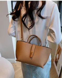 Detail of lychee pattern leather tote bag with elegant gold metal buckle and strap