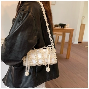 Close-up of white faux pearl woven mini bag featuring satin lining and ribbon detail
