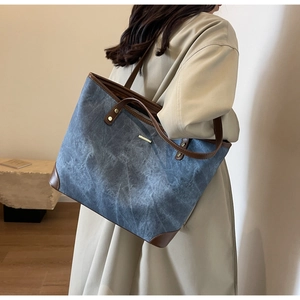 Detail of large navy canvas tote bag with brown leather handles worn by a model