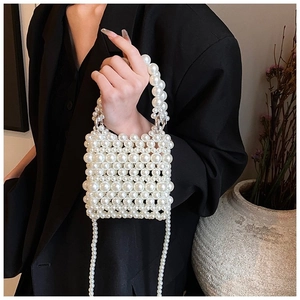 Close-up of handmade white pearl beaded mini bag with elegant chain strap on a blazer