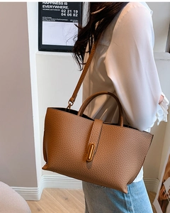 Close-up of brown lychee texture leather bucket bag with elegant gold oval buckle
