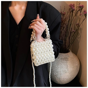 Close-up of handmade white pearl beaded handbag with elegant curved top handle and strap