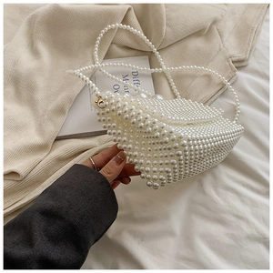 Detail of white pearl beaded flap bag featuring a golden moon pendant and shoulder strap