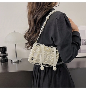 Detailed shot of white pearl woven bucket bag with satin bow on black dress