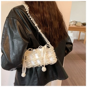 Detailed close-up of a handmade pearl woven crossbody bag with silk bow and satin lining