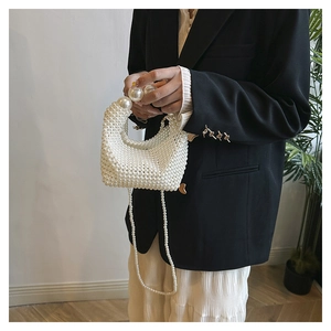 Detail of hand-woven pearl evening bag with large decorative pearls and metal strap