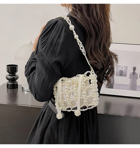 Detailed back view of a white woven pearl bucket bag on a black dress model