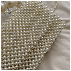 Detailed macro view of hand-woven pearl handbag with premium luster and texture