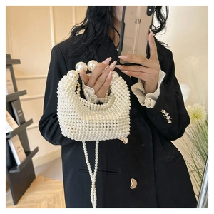 Detail of hand-woven pearl handbag with large decorative beads and long chain strap