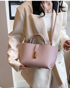 Detail of lavender pebble leather handbag with gold metal clasp on beige blazer