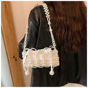 Detail of handmade pearl beaded crossbody bag featuring a delicate white ribbon bow