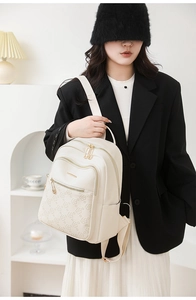 Detail view of cream faux leather backpack with floral embossing and gold hardware