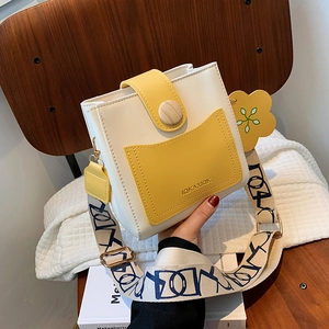 Sac seau chic bicolore blanc et jaune avec breloque fleurie et bandoulière à motifs