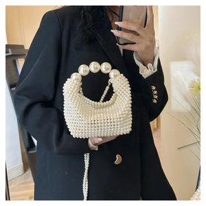 Detail of white pearl woven underarm bag featuring oversized pearls and metallic chain strap