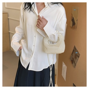 Detail of white pearl beaded handbag with dual chain straps and handcrafted weaving