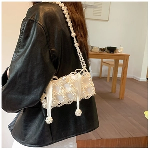 Detail of hand-woven pearl crossbody bag with satin liner shown on a black jacket