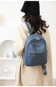Detail of grey-blue PU leather backpack with floral embossing and gold zipper accents