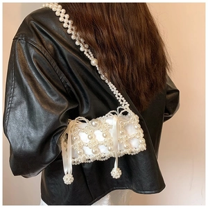 Detail of handmade white pearl woven crossbody bag with silk ribbon on leather jacket