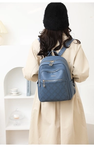 Detailed view of the blue leather backpack with embossed flowers on a female model
