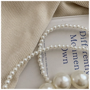 Detailed view of cream pearls in varying sizes on beige corduroy fabric for small handbag