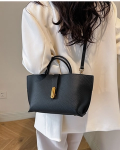 Detail view of black pebbled leather tote bag with gold buckle and stylish hand straps