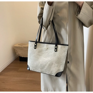 Detail of grey textured tote bag with black leather straps and gold hardware for office