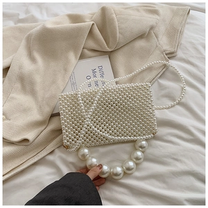 Close-up of white woven pearl handbag featuring a large pearl handle and flap closure